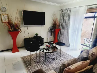 a living room with a couch and a tv at Red Peppers in Pretoria