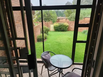 a glass table and chairs on a balcony with a view of a yard at Red Peppers in Pretoria