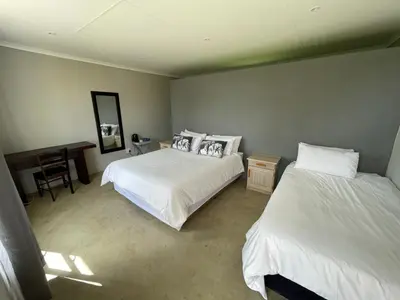 a bedroom with two beds and a desk and a table at Holbank River Lodge in Ermelo
