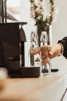 a person holding two glass bottles on a counter at 55 Tulbagh events and wedding venue in Kempton Park