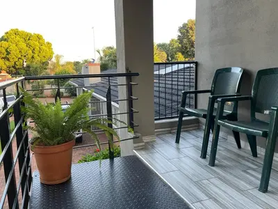 a balcony with two chairs and a plant at 22 on Mirabel in Kempton Park