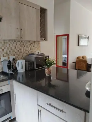 a kitchen with a black counter top and a microwave at The Classic Menlyn Maine Apartment in Pretoria