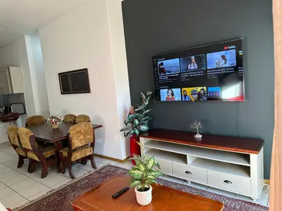 a living room with a table and a television on a wall at The Classic Menlyn Maine Apartment in Pretoria