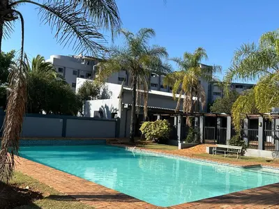 a swimming pool in front of a building with palm trees at The Classic Menlyn Maine Apartment in Pretoria