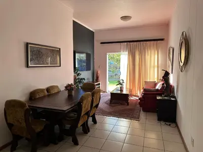 a living room with a dining room table and chairs at The Classic Menlyn Maine Apartment in Pretoria