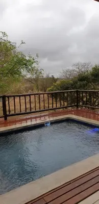 a swimming pool with a wooden fence around it at Stoep At Kruger in Komatipoort