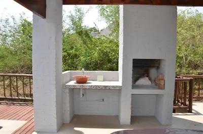 a outdoor kitchen with a fireplace on a deck at Stoep At Kruger in Komatipoort