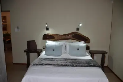 a bedroom with a bed with a wooden bird headboard at Stoep At Kruger in Komatipoort