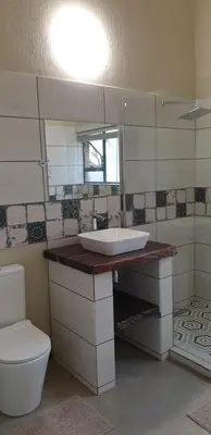 a bathroom with a sink and a toilet and a mirror at Stoep At Kruger in Komatipoort
