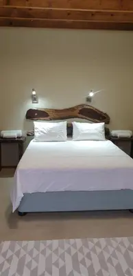 a bedroom with a large bed with white sheets and pillows at Stoep At Kruger in Komatipoort
