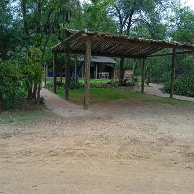 a wooden pavilion with a house in the background at The Aces - NUDE - SunEden Family Naturist Resort in Pretoria