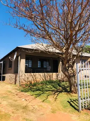 a house with a tree in front of a fence at Cipresso Guesthouse in Tierpoort