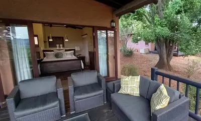 a porch with chairs and a bed in a bedroom at Bee-Eater Cottage, DaGama Dam in White River