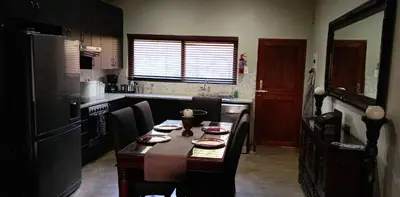 a kitchen with a table with chairs and a refrigerator at Bee-Eater Cottage, DaGama Dam in White River