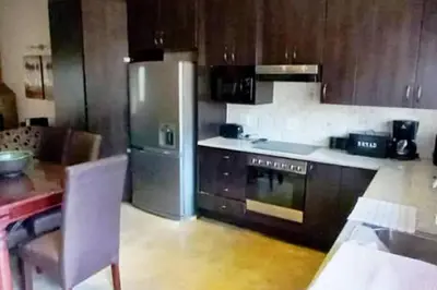 a kitchen with a stainless steel refrigerator and a table at Bee-Eater Cottage, DaGama Dam in White River
