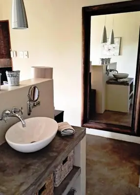 a bathroom with a sink and a large mirror at Bee-Eater Cottage, DaGama Dam in White River