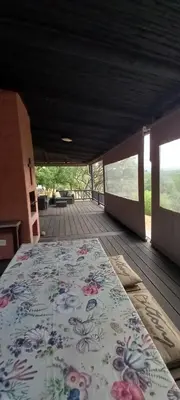 a covered porch with a bed on a deck at Bee-Eater Cottage, DaGama Dam in White River