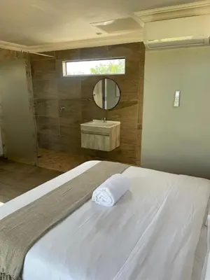 a bedroom with a bed and a sink and a mirror at Bluewave Farm Villa in Louis Trichardt