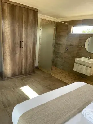 a bathroom with a shower and a bed and a sink at Bluewave Farm Villa in Louis Trichardt