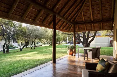 a patio with a table and a field of grass at Letamo at Qwabi Private Game Reserve by NEWMARK in Bela-Bela