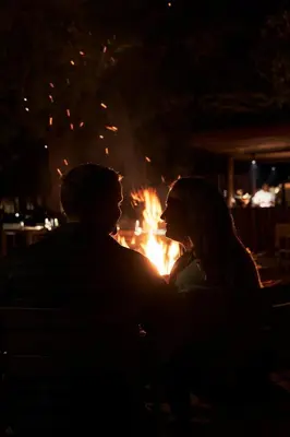 a man and a woman sitting in front of a fire at Letamo at Qwabi Private Game Reserve by NEWMARK in Bela-Bela
