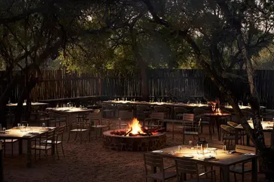 a group of tables and chairs around a fire pit at Letamo at Qwabi Private Game Reserve by NEWMARK in Bela-Bela