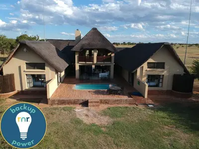 a house with a thatched roof and a swimming pool at Moshate Lodge Zebula 4 Bedroom Holiday home in Mabula