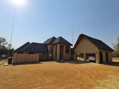 a house with four roofs on a dirt yard at Moshate Lodge Zebula 4 Bedroom Holiday home in Mabula