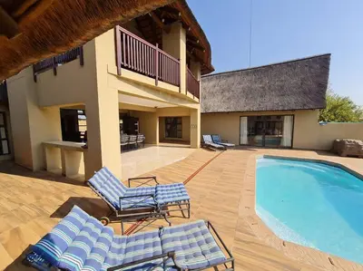 a patio with lounge chairs and a swimming pool at Moshate Lodge Zebula 4 Bedroom Holiday home in Mabula