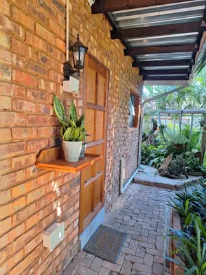 a brick building with a wooden door and a porch at Fraai Maraai Self Catering Apartments in Groblersdal