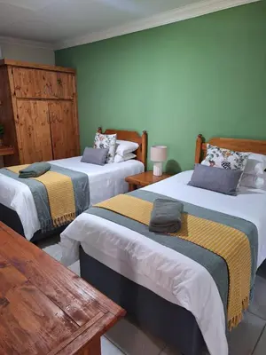 two beds in a room with green walls at Fraai Maraai Self Catering Apartments in Groblersdal