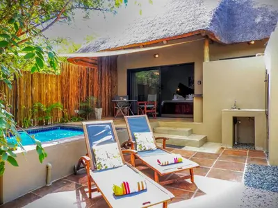 a villa with a swimming pool and two chairs at Braai Safaris Lodge in Hoedspruit