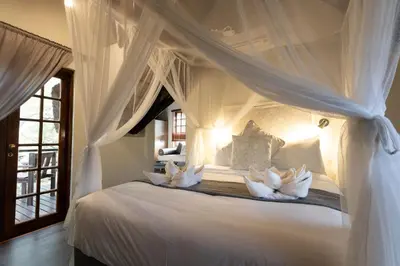 a bedroom with a white canopy bed with white pillows at Braai Safaris Lodge in Hoedspruit
