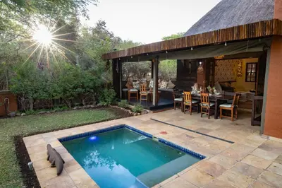 a backyard with a swimming pool and a table and chairs at Braai Safaris Lodge in Hoedspruit