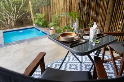 a table and chairs next to a swimming pool at Braai Safaris Lodge in Hoedspruit