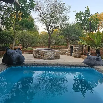 a swimming pool in a yard with a fire pit at Eye of Kruger - Spacious holiday home with splash pool and boma in Marloth Park
