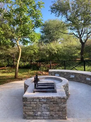 a stone fountain in a park with trees in the background at Eye of Kruger - Spacious holiday home with splash pool and boma in Marloth Park