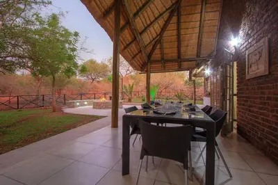 a patio with a table and chairs and a brick building at Eye of Kruger - Spacious holiday home with splash pool and boma in Marloth Park