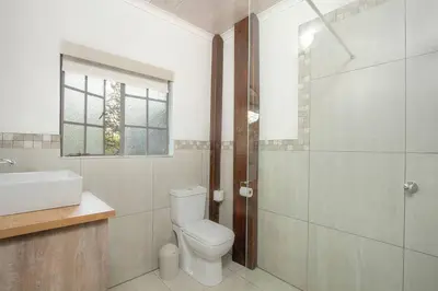 a bathroom with a toilet and a sink and a shower at Eye of Kruger - Spacious holiday home with splash pool and boma in Marloth Park