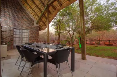 a black table with black chairs on a patio at Eye of Kruger - Spacious holiday home with splash pool and boma in Marloth Park
