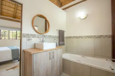 a bathroom with a sink and a tub and a mirror at Eye of Kruger - Spacious holiday home with splash pool and boma in Marloth Park