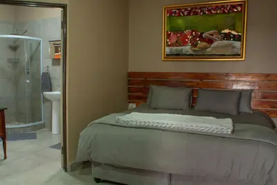 a bedroom with a bed and a bathroom with a shower at Casa de la Presa 4 in Polokwane