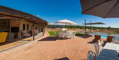 a patio with tables and chairs and an umbrella at Casa de la Presa 4 in Polokwane