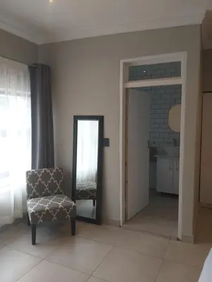a room with a mirror and a chair and a window at Kanyane @ Graskop in Graskop