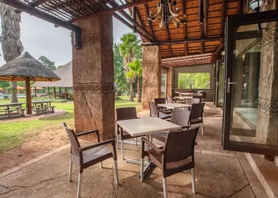 an outdoor patio with tables and chairs and an umbrella at Olifants River Lodge by Dream Resorts in Middelburg