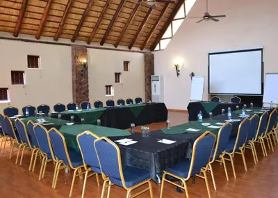 a conference room with tables and chairs and a screen at Olifants River Lodge by Dream Resorts in Middelburg