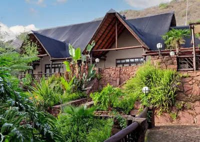 a house with a stone wall and plants at Olifants River Lodge by Dream Resorts in Middelburg