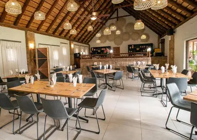 a dining room with wooden tables and chairs at Olifants River Lodge by Dream Resorts in Middelburg