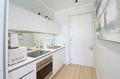 a white kitchen with a sink and a microwave at Ellipse Apartment in Midrand