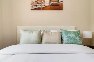 a white bed with colorful pillows on top of it at The Resting Nest Havilla in Midrand